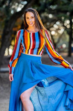 Muhteşem bir esmer model, sonbahar havasının tadını çıkarırken dışarıda poz veriyor.