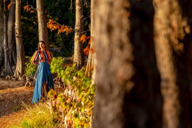 Muhteşem bir esmer model, sonbahar havasının tadını çıkarırken dışarıda poz veriyor.