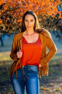 Muhteşem bir esmer model, sonbahar havasının tadını çıkarırken dışarıda poz veriyor.