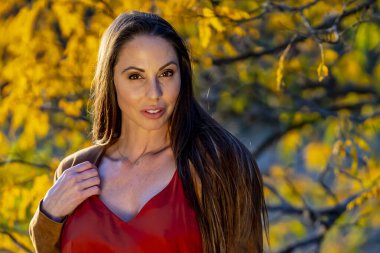 Muhteşem bir esmer model, sonbahar havasının tadını çıkarırken dışarıda poz veriyor.