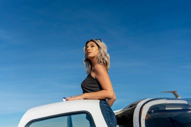 Sarışın bir model, yerel bir havaalanında tek motorlu bir uçakla dışarıda poz veriyor.