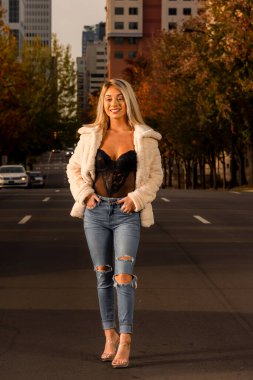 Genç ve güzel bir sarışın model, bir sonbahar gününün tadını çıkarırken dışarıda poz veriyor.