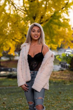 Genç ve güzel bir sarışın model, bir sonbahar gününün tadını çıkarırken dışarıda poz veriyor.