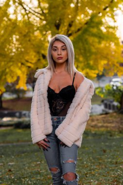 Genç ve güzel bir sarışın model, bir sonbahar gününün tadını çıkarırken dışarıda poz veriyor.