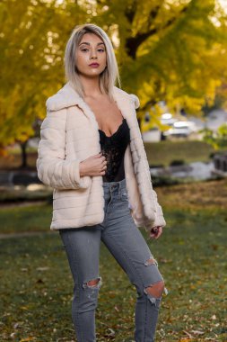 Genç ve güzel bir sarışın model, bir sonbahar gününün tadını çıkarırken dışarıda poz veriyor.