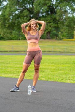 Muhteşem bir sarışın spor mankeni bir parkta yaz gününün tadını çıkarıyor.