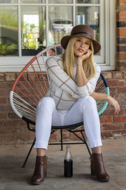 Sonbahar kıyafetleriyle dışarıda poz veren güzel bir sarışın manken.