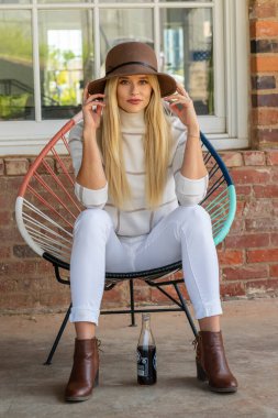 Sonbahar kıyafetleriyle dışarıda poz veren güzel bir sarışın manken.