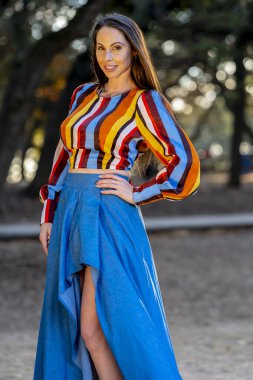 Muhteşem bir esmer model, sonbahar havasının tadını çıkarırken dışarıda poz veriyor.