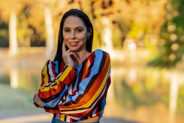 Muhteşem bir esmer model, sonbahar havasının tadını çıkarırken dışarıda poz veriyor.