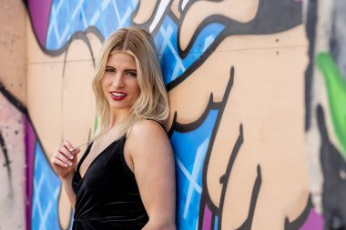 Sonbahar kıyafetleriyle dışarıda poz veren güzel bir sarışın manken.