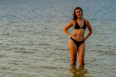 Güzel bir esmer bikini mankeni sahilde açık havanın tadını çıkarır.