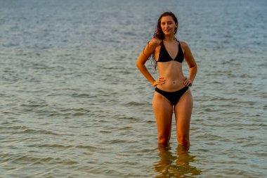 Güzel bir esmer bikini mankeni sahilde açık havanın tadını çıkarır.