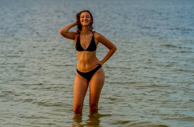 Güzel bir esmer bikini mankeni sahilde açık havanın tadını çıkarır.