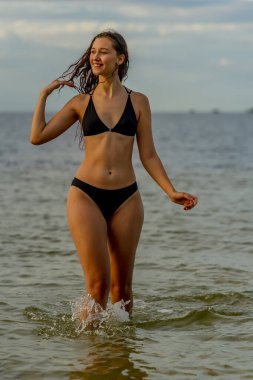 Güzel bir esmer bikini mankeni sahilde açık havanın tadını çıkarır.