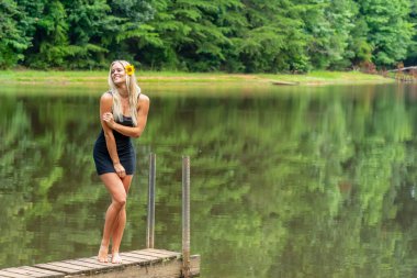 Muhteşem sarışın bir manken, yaz gününün tadını çıkarırken göletin kenarında poz veriyor.