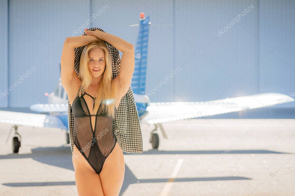 A beautiful blonde model poses with a small general aircraft
