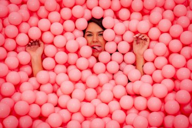 Güzel bir Asyalı model büyük miktarda plastik toplarla renkli bir odada oynar.