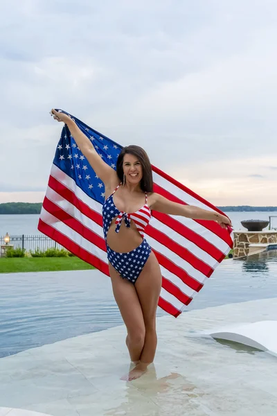 アメリカの国旗を掲げながら愛国的なアメリカのビキニを着た女性の肖像 — ストック写真