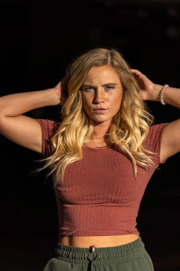 Muhteşem sarışın bir model, bir sonbahar günü park yerinde poz verir.