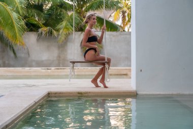 Meksika, Merida yakınlarındaki Yucatan Yarımadası 'nda beyaz bir duvara karşı güzel sarışın bir üstsüz manken.