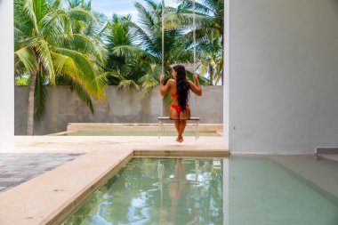 Güzel bir esmer model, Meksika, Merida yakınlarındaki Yucatan Yarımadası 'nda bir palmiye ağacının altında yumuşak ışığın tadını çıkarıyor.