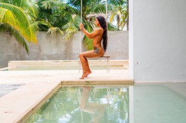 Güzel bir esmer model, Meksika, Merida yakınlarındaki Yucatan Yarımadası 'nda bir palmiye ağacının altında yumuşak ışığın tadını çıkarıyor.