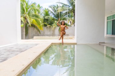 Güzel bir esmer model, Meksika, Merida yakınlarındaki Yucatan Yarımadası 'nda bir palmiye ağacının altında yumuşak ışığın tadını çıkarıyor.