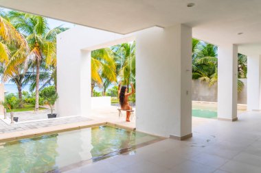 Güzel bir esmer model, Meksika, Merida yakınlarındaki Yucatan Yarımadası 'nda bir palmiye ağacının altında yumuşak ışığın tadını çıkarıyor.