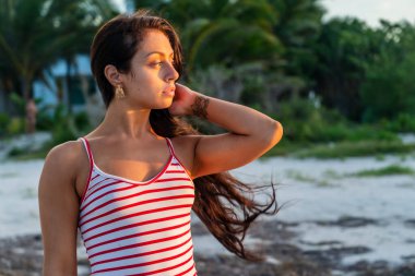 Güzel bir esmer model, Meksika, Merida yakınlarındaki Yucatan Yarımadası 'nda bir palmiye ağacının altında yumuşak ışığın tadını çıkarıyor.