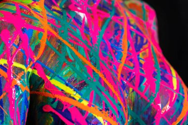 Çıplak bir kadın ev ortamında renkli boya ile boyanır.