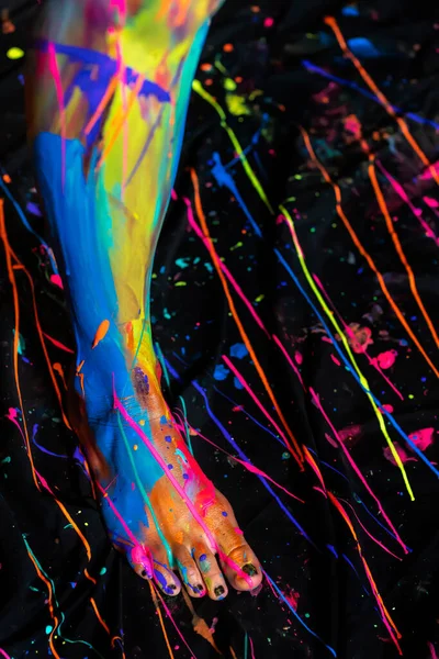 A naked woman is painted with colorful paint in a home environment