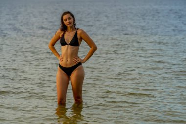 Güzel bir esmer bikini mankeni sahilde açık havanın tadını çıkarır.