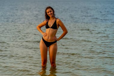 Güzel bir esmer bikini mankeni sahilde açık havanın tadını çıkarır.