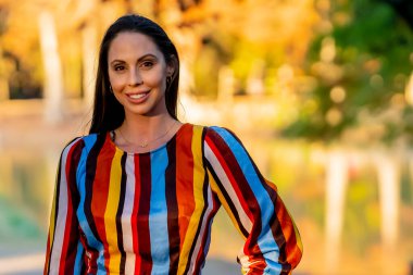 Muhteşem bir esmer model, sonbahar havasının tadını çıkarırken dışarıda poz veriyor.