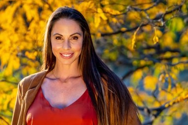 Muhteşem bir esmer model, sonbahar havasının tadını çıkarırken dışarıda poz veriyor.