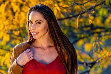 Muhteşem bir esmer model, sonbahar havasının tadını çıkarırken dışarıda poz veriyor.