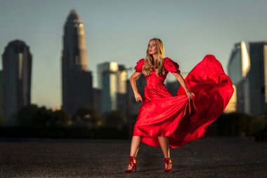 Sarışın bir manken gece elbisesiyle dışarıda poz veriyor.