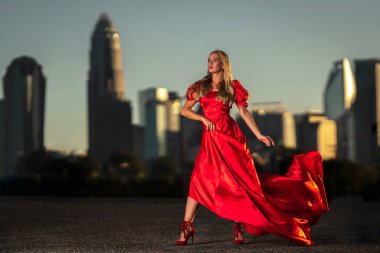 Sarışın bir manken gece elbisesiyle dışarıda poz veriyor.