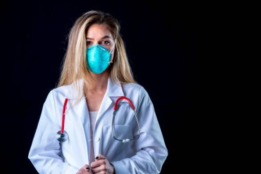 Genç bir doktor stüdyo ortamında N95 maskesiyle poz veriyor. 