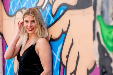 Sonbahar kıyafetleriyle dışarıda poz veren güzel bir sarışın manken.