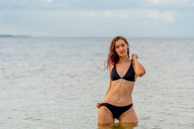 Güzel bir esmer bikini mankeni sahilde açık havanın tadını çıkarır.