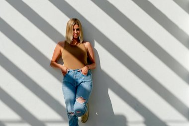 Sarışın bir model bahar kıyafetleriyle dışarıda poz veriyor.