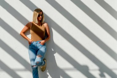 Sarışın bir model bahar kıyafetleriyle dışarıda poz veriyor.