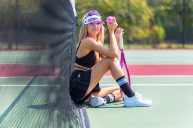 Güzel bir sarışın manken sıcak bir yaz gününde tenis oynar.