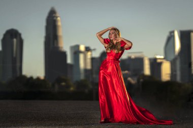 Sarışın bir manken gece elbisesiyle dışarıda poz veriyor.