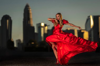 Sarışın bir manken gece elbisesiyle dışarıda poz veriyor.