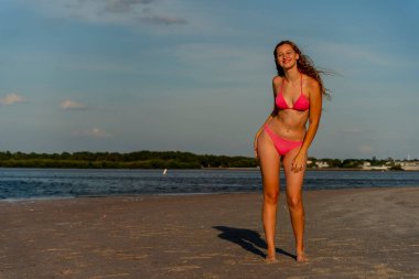 Güzel sarışın bir bikini mankeni sahilde açık havanın tadını çıkarıyor.