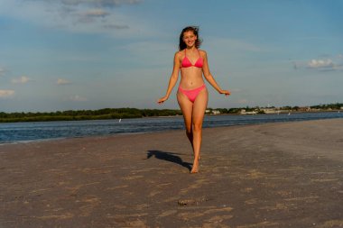 Güzel sarışın bir bikini mankeni sahilde açık havanın tadını çıkarıyor.