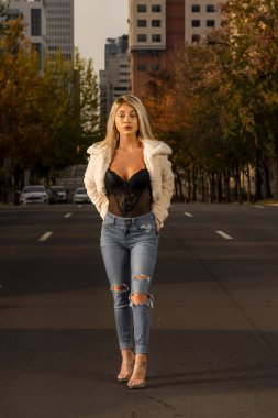 Genç ve güzel bir sarışın model, bir sonbahar gününün tadını çıkarırken dışarıda poz veriyor.